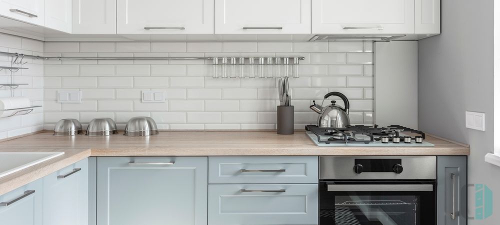 A modern kitchen with light gray cabinets and a classic subway tile backsplash