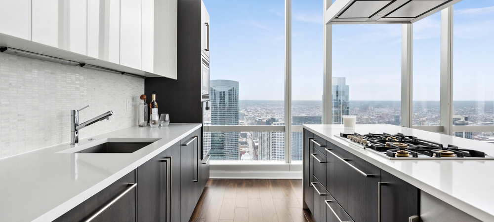 Modern kitchen with white upper cabinets and dark lower cabinets, city view.